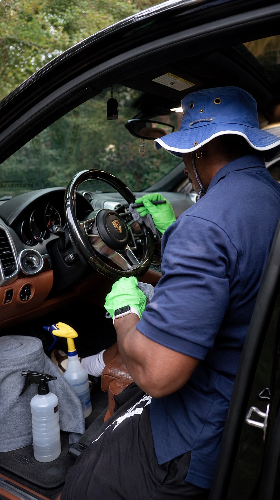 A Foamo detailer in a blue polo cleaning a Porsche Cayenne interior
