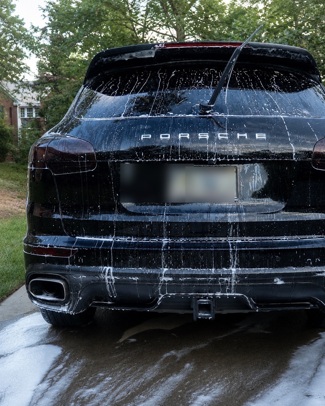 A foam-covered black Porsche Cayenne in a suburban driveway